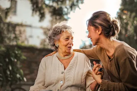 Elderly woman and caregiver sharing a moment of connection, representing caregiver support resources from Thrive at Home Network