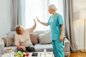 A professional caregiver high-fiving an older adult in a cozy living room, symbolizing trust and companionship in aging in place home care. Discover local care services through Thrive at Home Network.