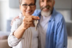 Happy Senior Couple Holding Home Keys, Showing To Camera. Thrive at Home Network Senior Moving Services