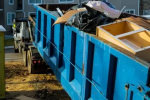 Large blue dumpster truck containing junk.